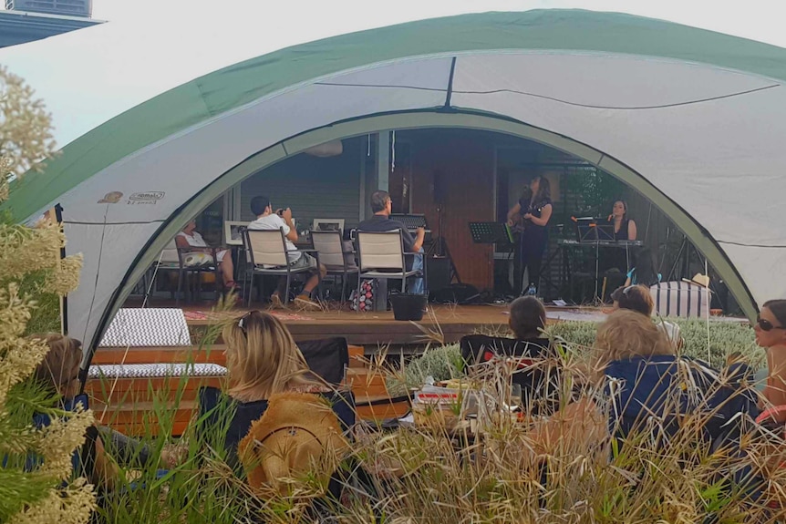 Musicians on a stage seen through a tent awning
