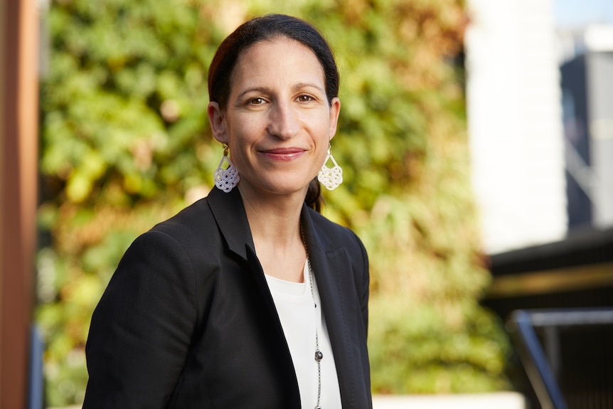 Woman in white shirt and black blazer smiles at camera 