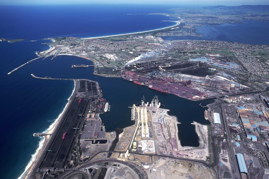 aerial of bhp steelworks, a large industrial complex surrounded by blue ocean