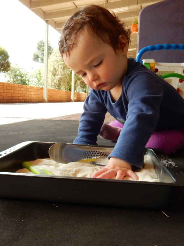 Baby sits outsits playing with play-doh