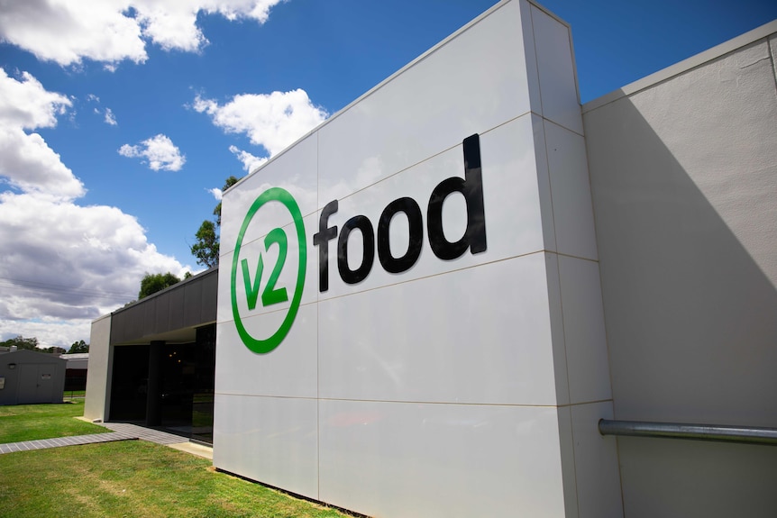 A sign reads v2food out front of a factory building.