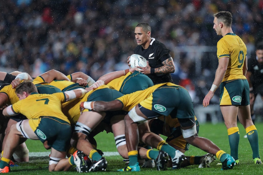Aaron Smith stands next to a scrum between Australia and New Zealand