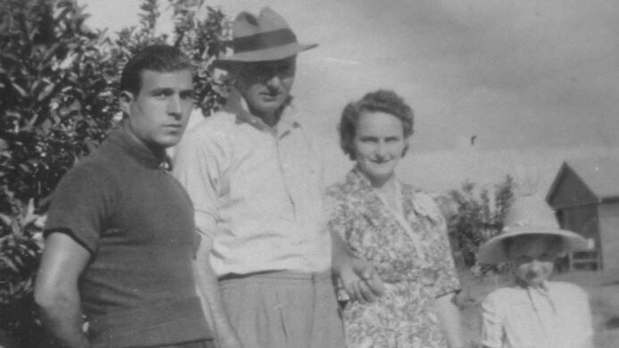 An old black and white photo of an Italian man standing with a married farming couple and their young daughter.