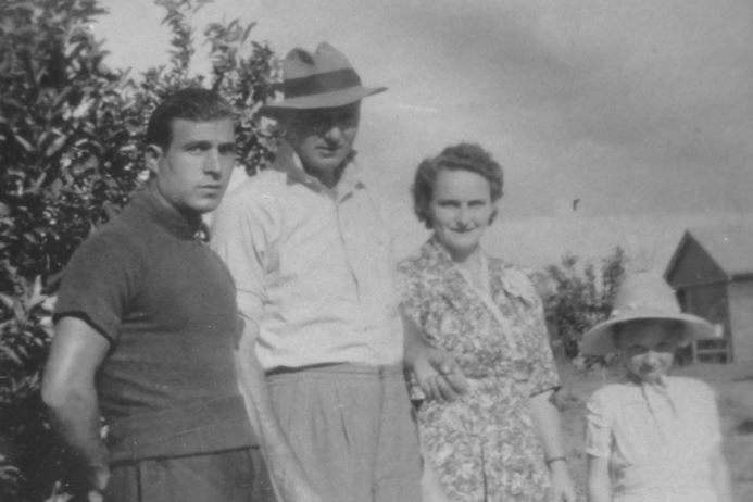 An old black and white photo of an Italian man standing with a married farming couple and their young daughter.