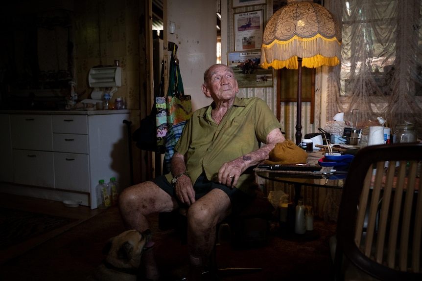 An older man sitting at home in his kitchen.
