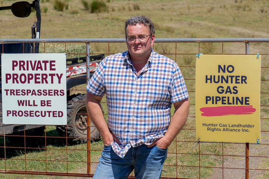 Mick Fetch stands in front of a fence with a sign reading "No Hunter Gas Pipeline,' near Maitland, October 2023.