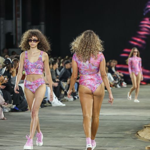 Three models in swimsuits walking down the runway in different directions