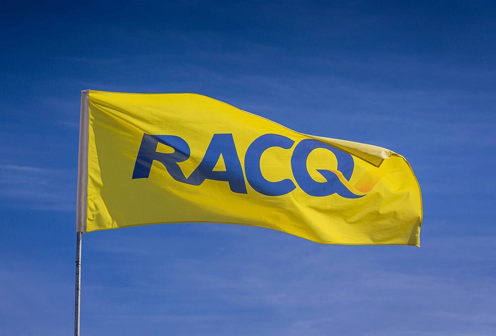 A yellow RACQ flag flies in a blue sky