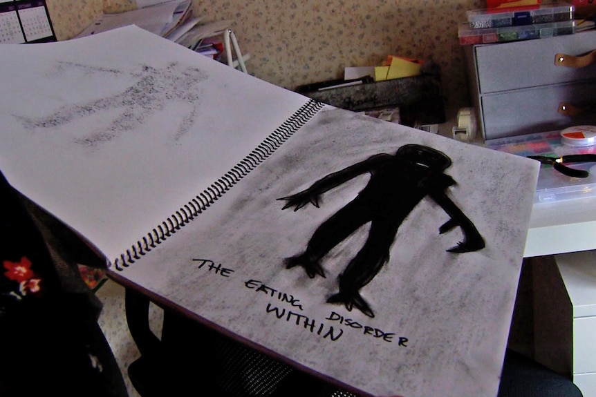 A spiral bound notebook open to a page with a sketch of a black monstrous figure with the caption 'the eating disorder within'.
