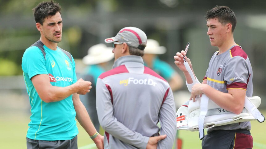 Mitchell Starc and Matthew Renshaw speak with a Queensland team official at a net training session in Brisbane.