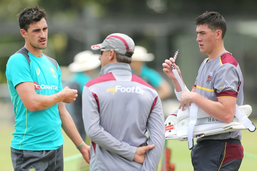 Mitchell Starc and Matthew Renshaw speak with a Queensland team official at a net training session in Brisbane.