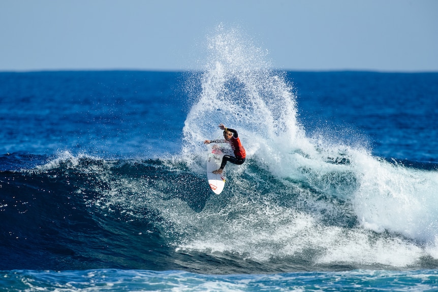 A man on a white surfboard whipping through waves