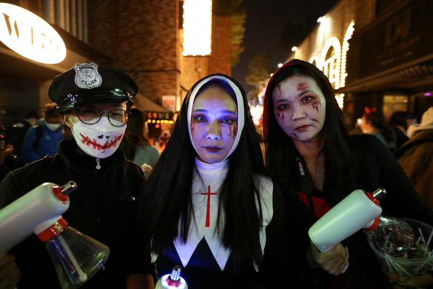 Three young women in Halloween costumes at night
