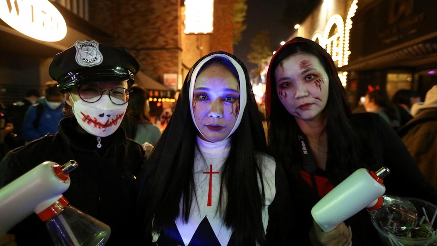 Three young women in Halloween costumes at night