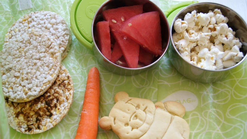 Rice cakes, watermelon, a carrot and popcorn on a table.