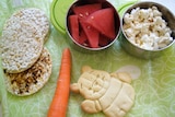 Rice cakes, watermelon, a carrot and popcorn on a table.