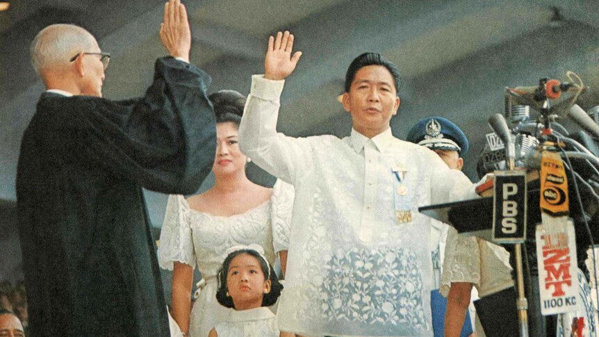 Ferdinand Marcos takes the Oath of Office by holding his hand in the air.