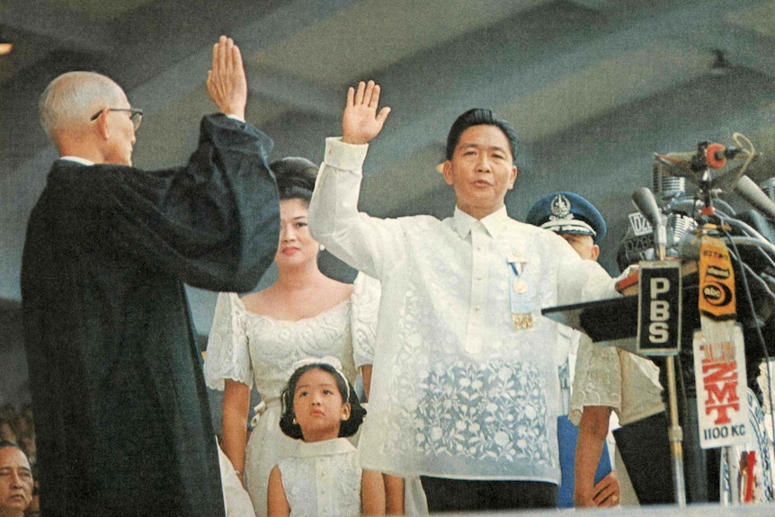 Ferdinand Marcos takes the Oath of Office by holding his hand in the air.