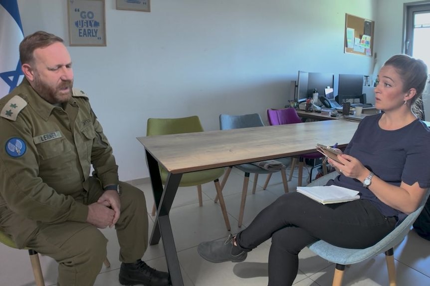 IDF officer sitting opposite a journalist in an interview for TV.