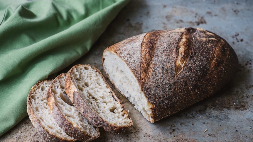 Sprouted Wheat Loaf from Brasserie Bread, sliced on a bread board.