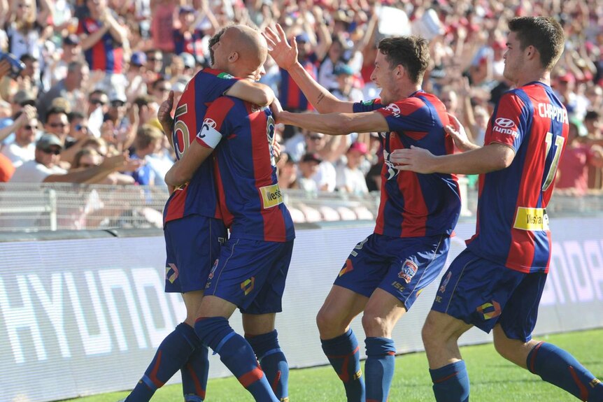 Craig Goodwin celebrates with his Jets team-mates after scoring the opening goal against Sydney FC.