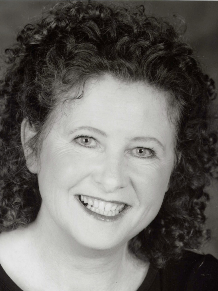 Black and white portrait of a middle aged woman with dark, curly, brown hair. 