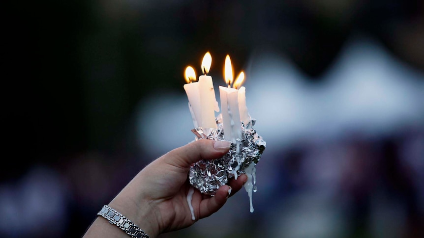 A woman holds candles during Aurora memorial service