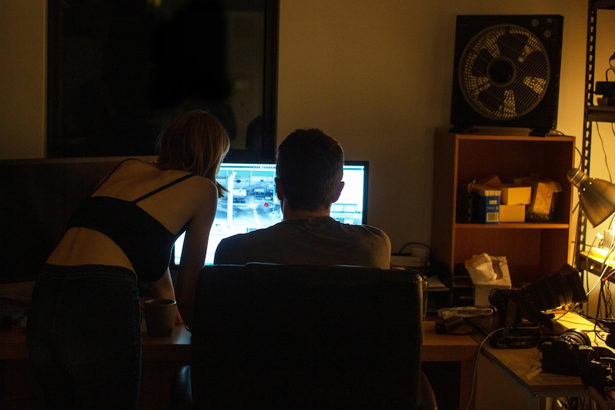 A woman and man are seen looking at a computer screen.