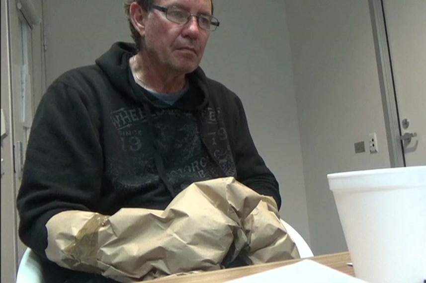 A man wearing paper bags on his hands