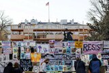 A fence covered in protest signs outside the White House