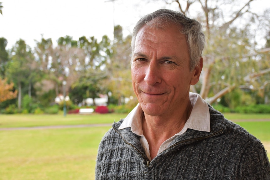 A man in a park looks at the camera.