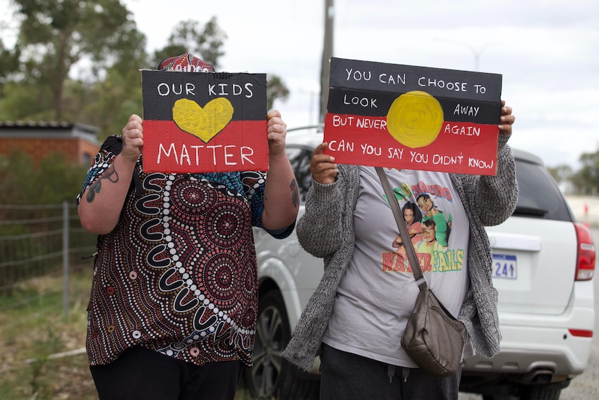 Protesters at a rally against conditions at Banksia Hill detention centre holding up signs.