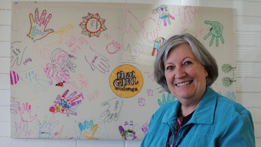 Gateway's Health Tricia Hazeleger stands in front of a mural that has drawings of women's and words of respect on it.