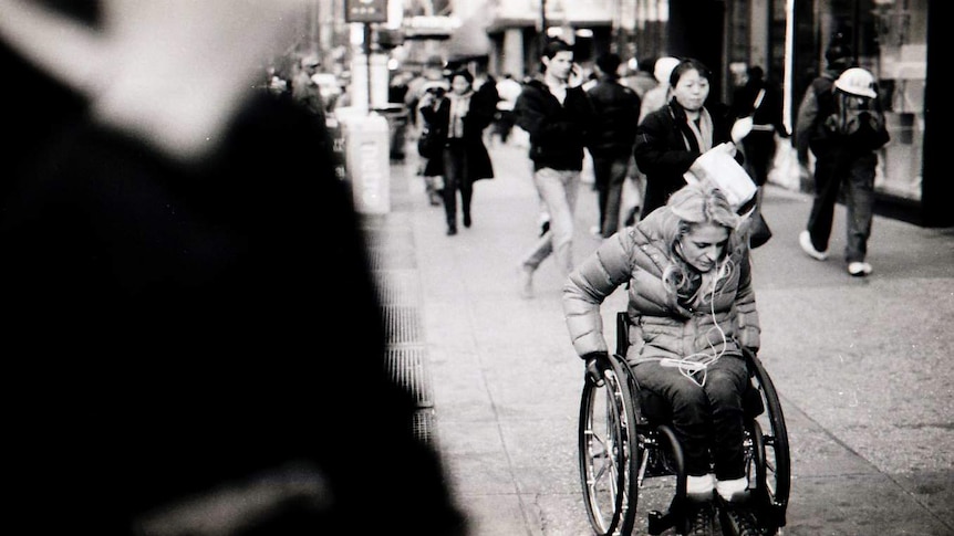 Woman in a wheelchair on a busy street