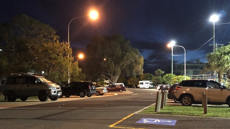 Cars and vans parked on a street at night