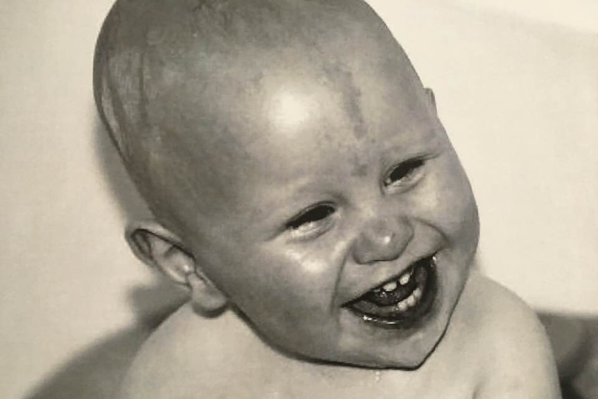 A black and white close up shot of a smiling baby.