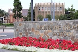 Sign reading Brisbane Grammar School with the school grounds behind.