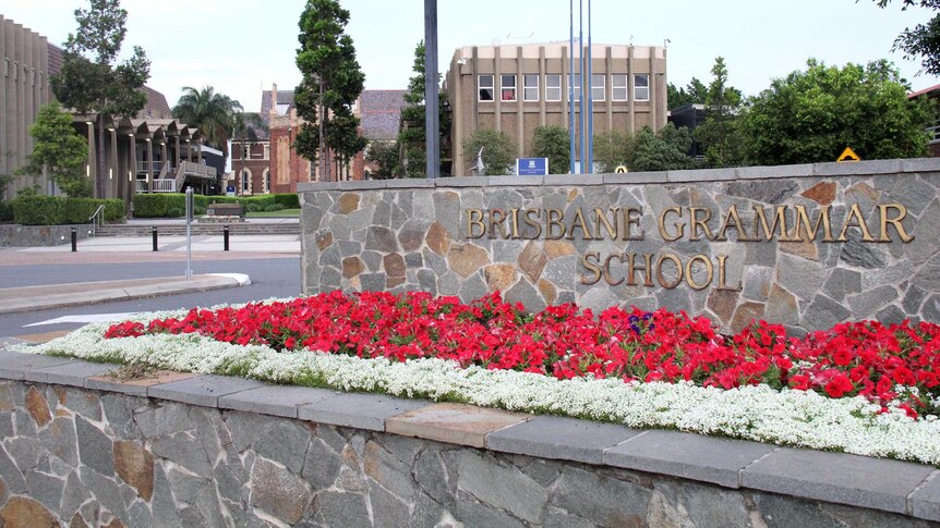 Sign reading Brisbane Grammar School with the school grounds behind.