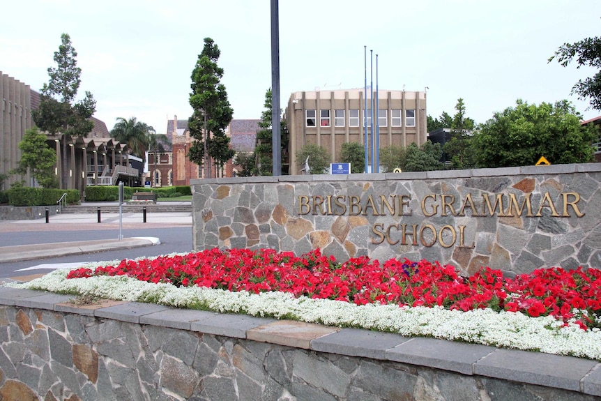 Sign reading Brisbane Grammar School with the school grounds behind.