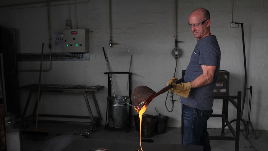 Man pouring molten glass onto a steel bench