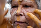 Close up of woman as ochre is applied to her face