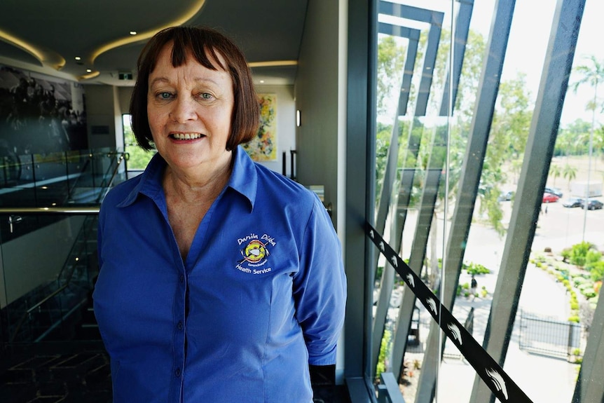 Olga Havnen stands in a conference room and smiles at the camera.