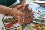 An older woman's hands grasping a glass mug.