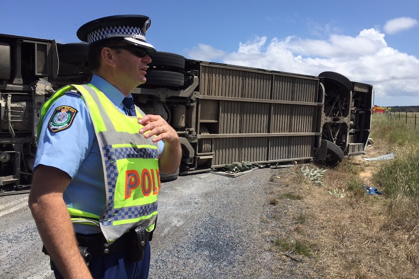 A police officer in front of the overturned Australian Defence Force bus.