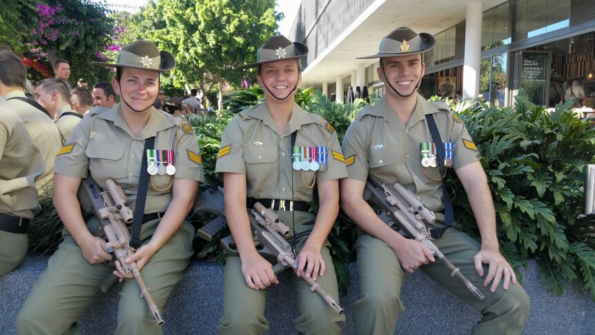 Three smiling soldiers sitting in the shade
