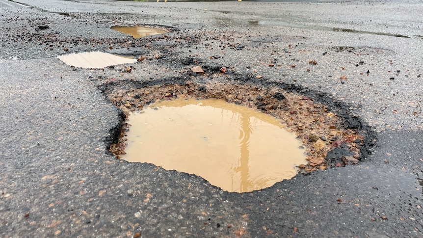 Large pothole filled with water on the road