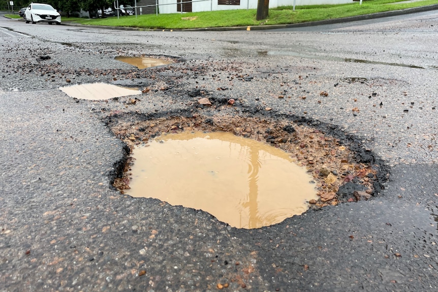 Large pothole filled with water on the road