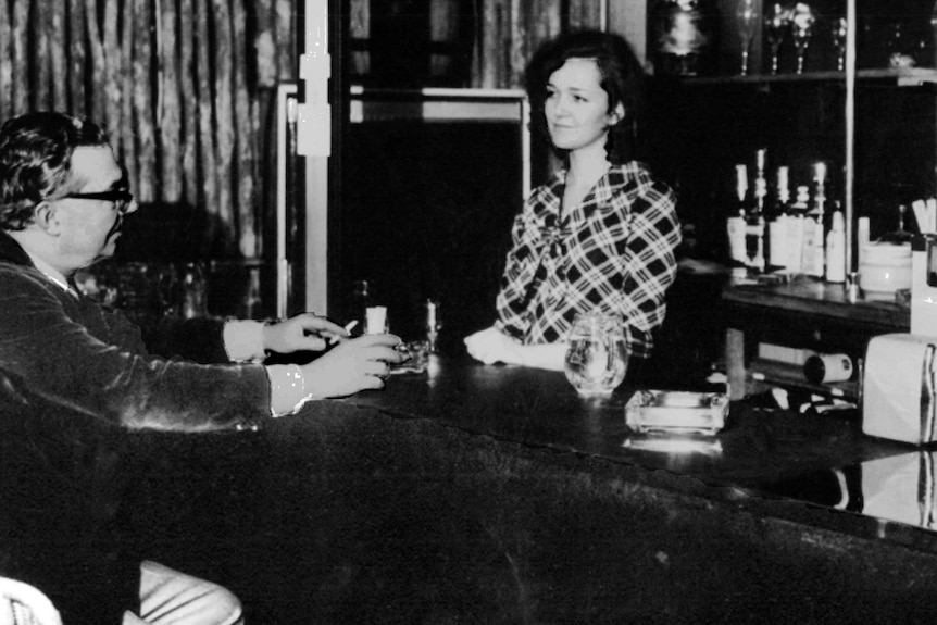 a black and white photo of a man and woman at a bar