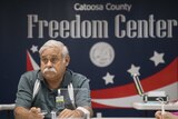 A man sits at a desk in front of a sign that reads "Catoosa County Freedom Center".