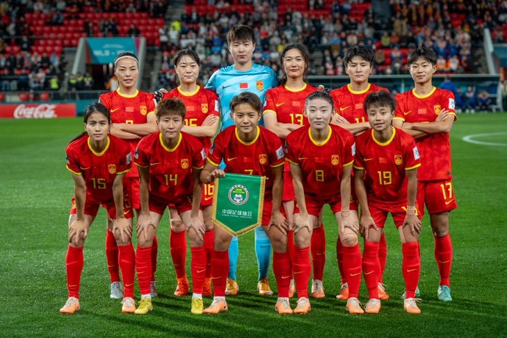 A Chinese team of footballers stands together for a group picture before a game.